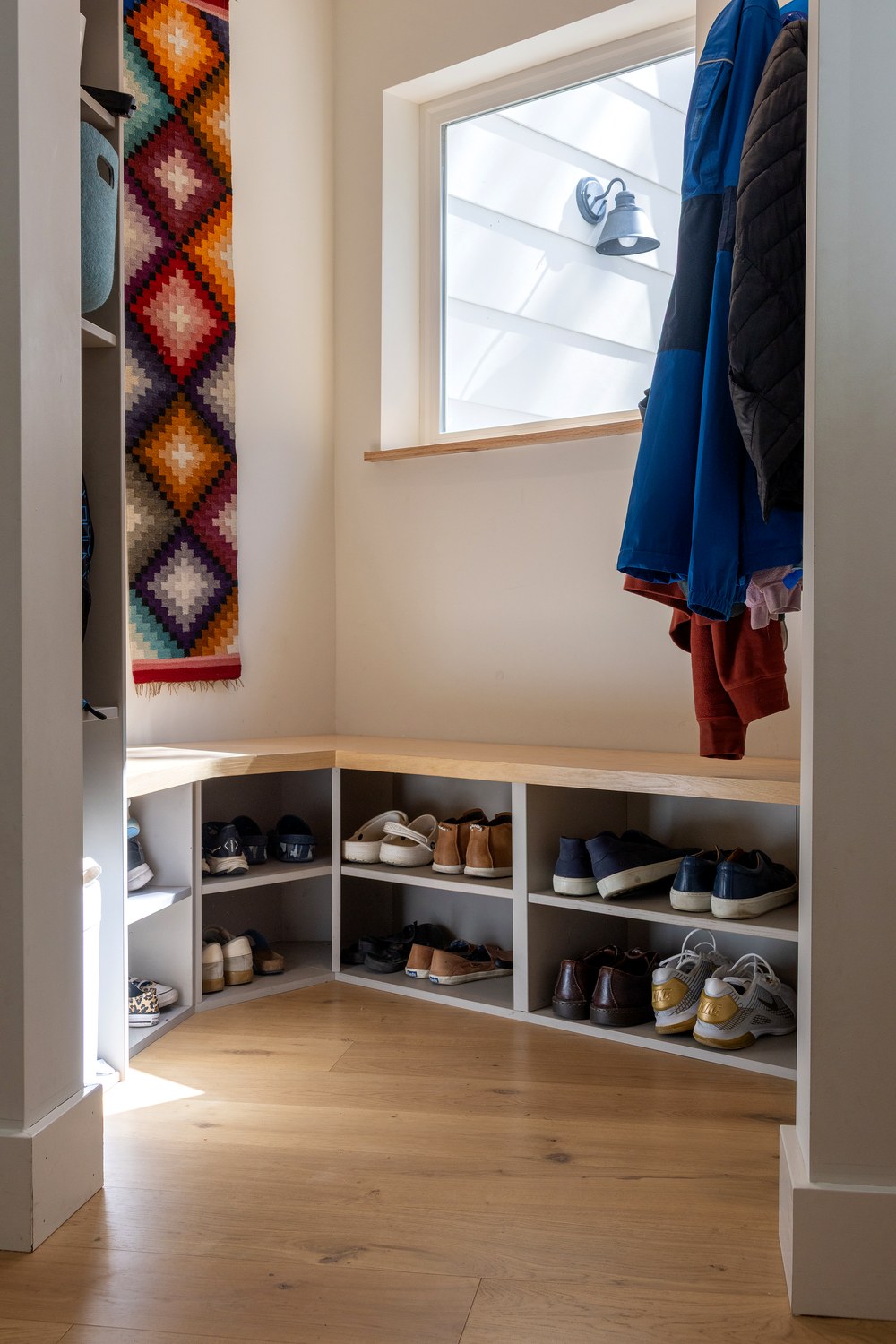 Mudroom bench and storage tower beside a window