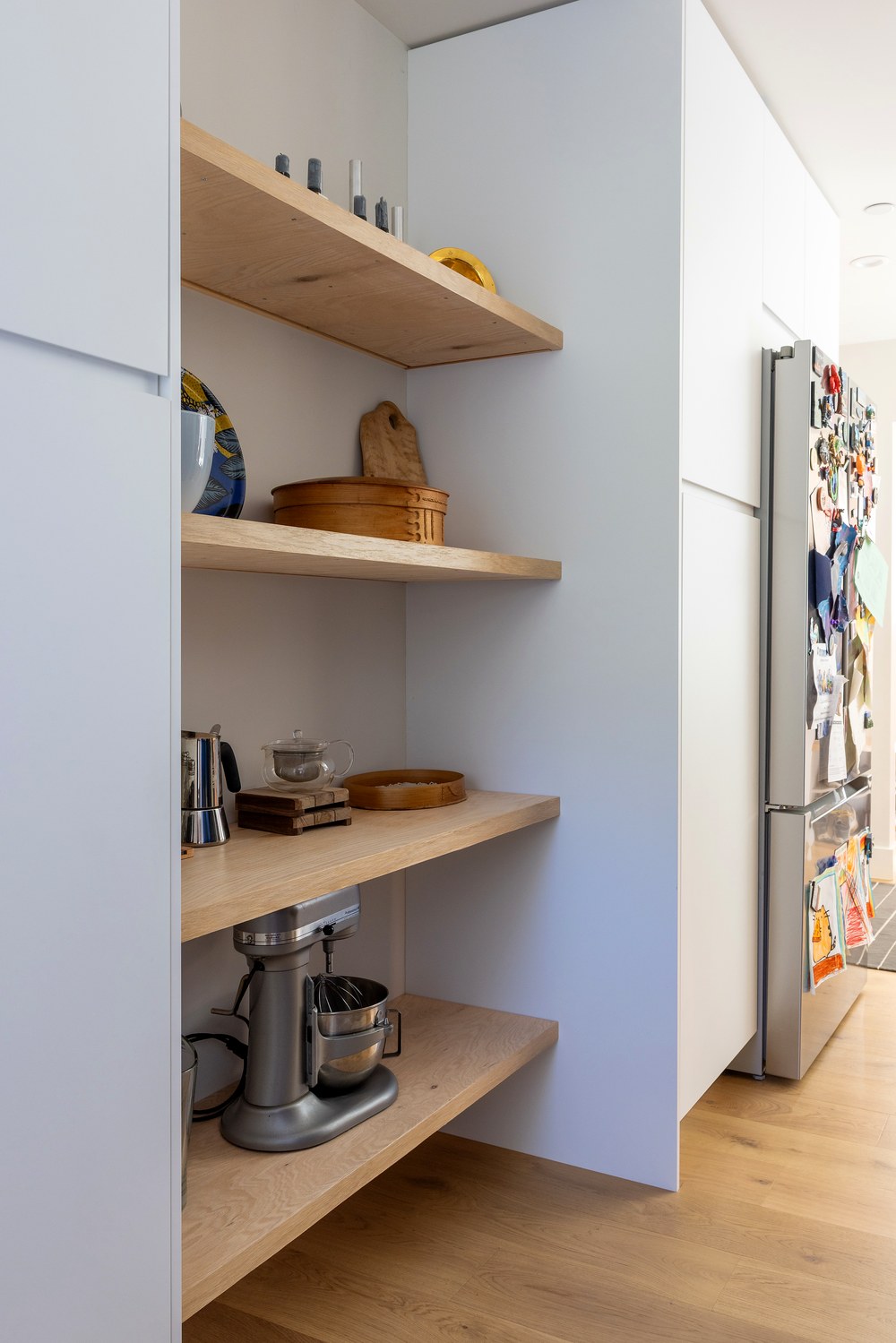 Pantry shelving built into a nook beside the refrigerator