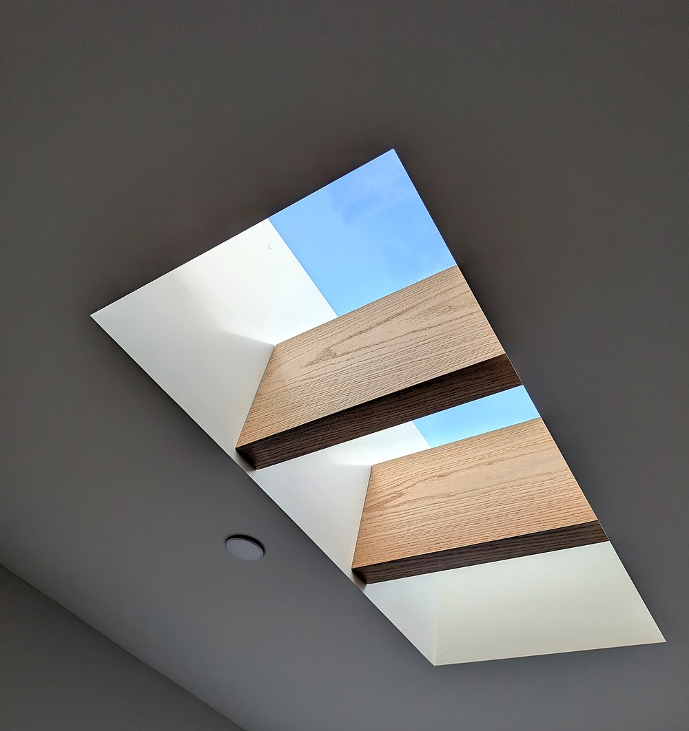 Close-up looking up through a skylight with oak beams and blue sky