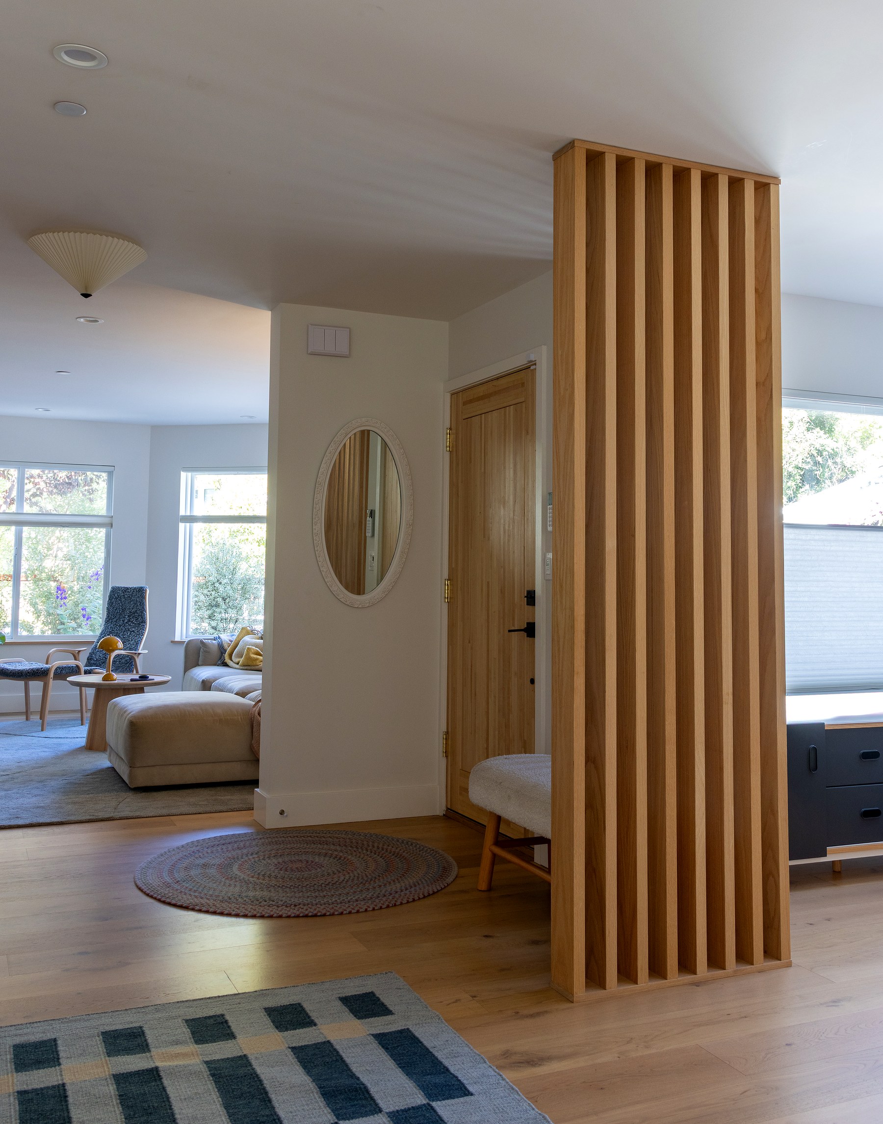 Oak slat partition wall with light passing through into the entry